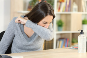 Woman sneezing into her elbow